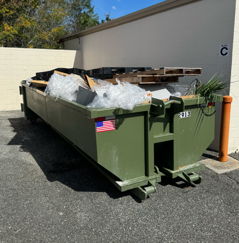 Large green construction dumpster filled with debris at a commercial site in Jacksonville